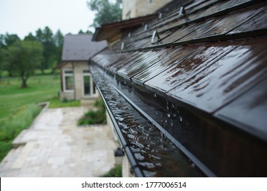 Rain Flowing Down A Tile Roof Into Gutter