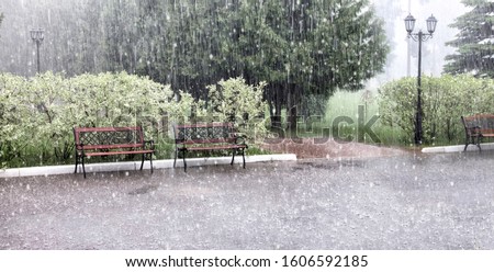 Rain and hail on a summer day. Large puddles on the sidewalk during heavy rain. Heavy rain with snow and hail in the Park. Wet benches on the paved path. Spray from drops and bubbles in large puddles. Stock photo © 