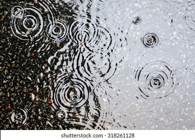 Rain on asphalt or tarmac road creating ripples, high contrast during autumn.