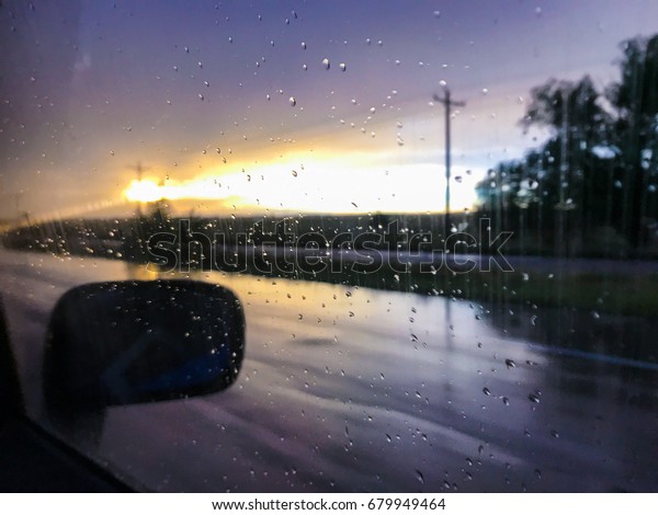 Rain on car window during\
sunset