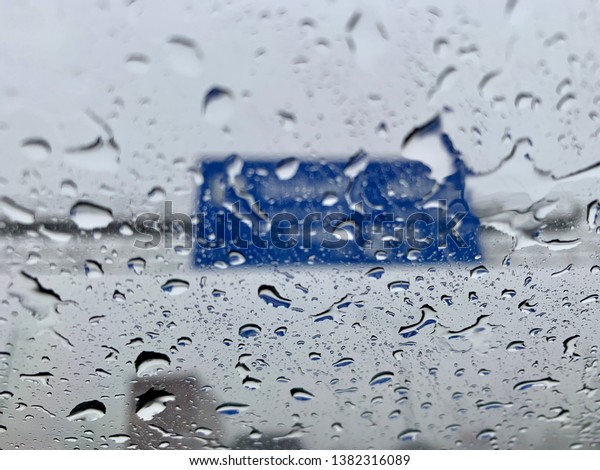 Rain on the car window has a blue background of\
road signs, for abstract and\
text.