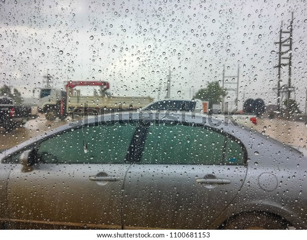 Rain on car windshield at construction\
site. Raining cats and dogs. It\'s raining so hard.\
