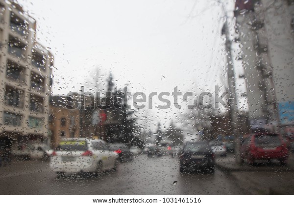 rain on the city\
street through a car windshield. Rain drops on window, rainy\
weather. inside car when\
rainning