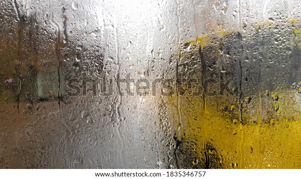 Rain on the rear window of a car in autumn.\
Inside view of the road with moving cars in the city through the\
window from the car with rain drops. driving a car in the field of\
view of the rear window.