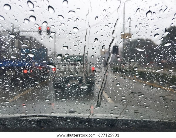 Rain on the windshield while driving at the red\
light intersection in\
Thailand.