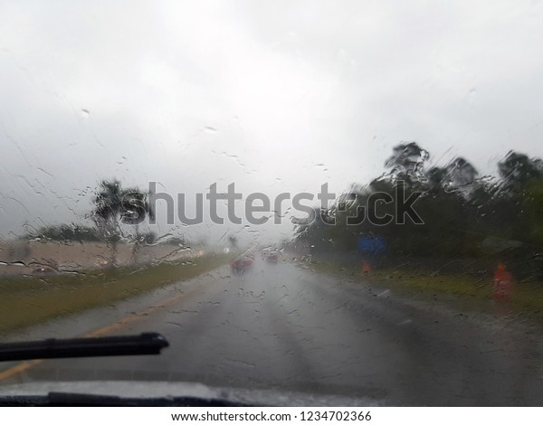 rain outside the car window, view of the road\
along the road. rainy season storm raining car driving get ready,\
travel concept. soft\
focus.