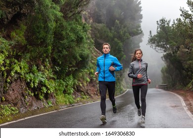 Rain Run Fit People Training Jogging In Rain Weather Wearing Cold Clothing Running Outdoors In Nature Autumn Season. Active Couple On Wet Park Trail Jogging. Asian Woman, Caucasian Man Athletes.