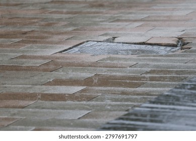 Rain striking the pavement and creating dynamic water patterns