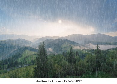 Rain and sun through the clouds over the green summer Carpathian foggy mountain hills. Rainy evening panorama. - Shutterstock ID 1976533832