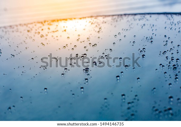 The rain that hits the windshield Is a beautiful\
clear droplet With the background  that has shadows reflected by\
light Makes the image look dimensional, fresh, wet, juicy, giving a\
cool feeling.