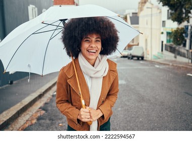 Rain, umbrella and city with a walking black woman in the street during a cold or wet winter day. Water, insurance and cover with a young afro female outdoor for a walk in an urban town road