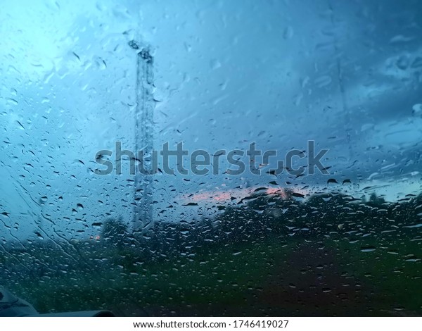 Rain water drops on car wind\
shield.looking at a cloudy. closeup - road background- image\
