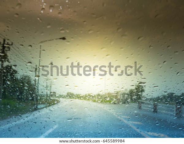 Rain and water drops on glass or mirror of car.\
The road and sky and clouds. Water is a hindrance to travel. Driver\
must be careful in driving. Because rain drop will make us see\
street more difficult
