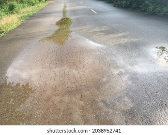 Rain Water In The Puddle In Cracked Asphalt Road