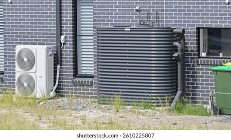 Rain water tank and air conditioning unit on the side of a brick house