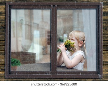 Rain, Window Of A House. Outside The Window, A Little Girl In The Apartment. Girl Smelling A Bouquet Of Flowers. The House Is Warm And Cozy. Outside The Storm