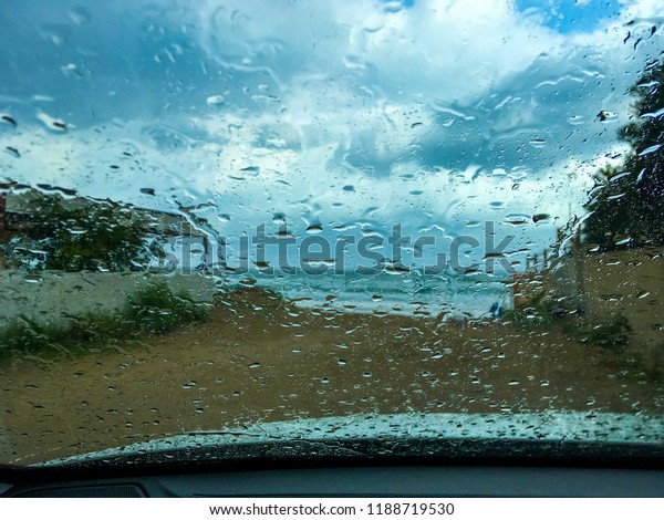 Rain in the windshield of a car with the sea\
in the background
