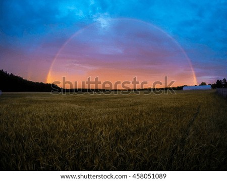 Foto Bild Wolkenformation die wie ein Vogel aussieht über einem abgeernteten Feld mit Strohballen.