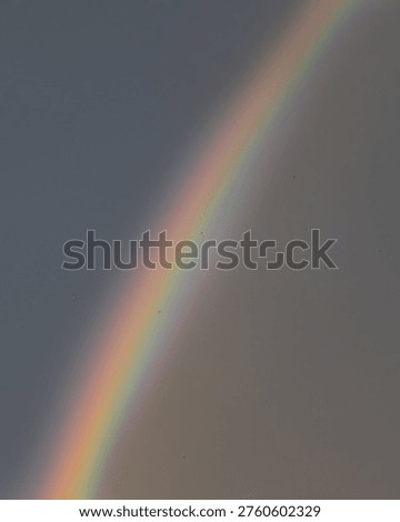 Rainbow appearing in a cloudy sky with soft light, natural atmospheric phenomenon with minimal composition.