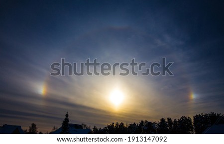 Rainbow around sun is called sundogs also known as parhelion, parhelia. Rare weather effect in winter in cold weather. Sun reflecting from ice crystals. 
