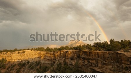 A rainbow and the beginnings of a double rainbow arc over the peak of Smithsonian Butte seen from the northern rim of Gooseberry Mesa in Southern Utah, USA on a stormy summer afternoon.