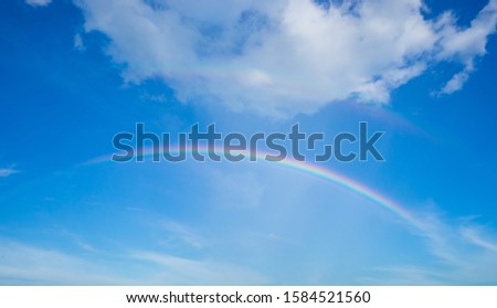 Rainbow and blue sky with white cloud.