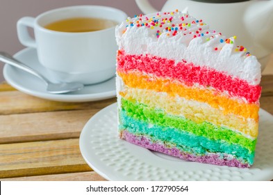 Rainbow cake with white tea cup on the wood table