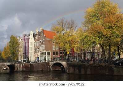 Rainbow in cloudy sky above trees on a canal in autumn in Amsterdam, Holland