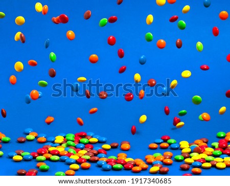 Rainbow Colored Candy Coated Chocolate Buttons Falling into a Pile