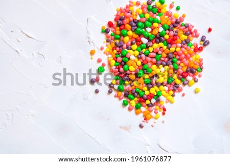 Rainbow colored candy nerds sprinkled on a white background.