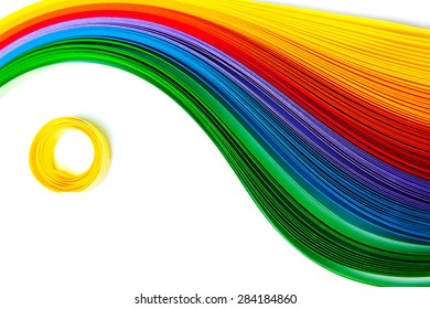 Rainbow colored quilling paper laid out in waves and shapes