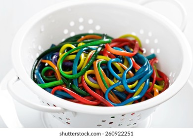 Rainbow colored spaghetti in a white colander