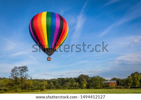 Rainbow colorful hot-air balloon floats on a summer morning with bright blue sky 