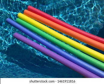 Rainbow Coloured Pool Noodles Floating In A Swimming Pool. Fun Summer Vibes.