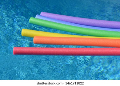 Rainbow Coloured Pool Noodles Floating In A Swimming Pool. Fun Summer Vibes.