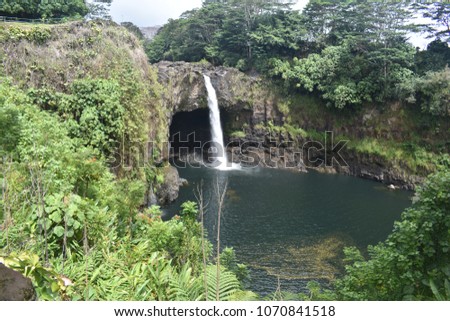Rainbow Falls Downtown Hilo Hawaii Waterfall cascading down a rocky alcove into a pool surrounded by jungle
