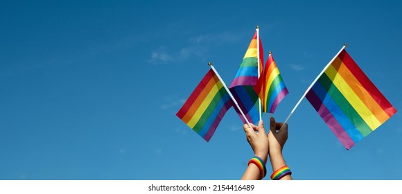 Rainbow Flags Showing In Hands Against Clear Bluesky, Copy Space, Concept For Calling All People To Support And Respcet The Genger Diversity, Human Rights And To Celebrate Lgbtq+ In Pride Month.