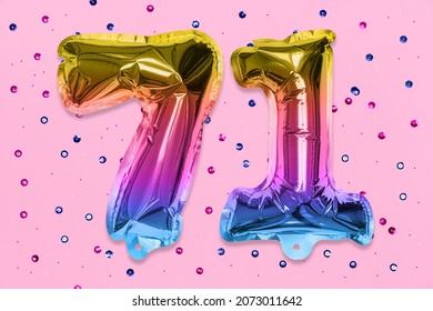 Rainbow foil balloon number, digit seventy one on a pink background with sequins. Birthday greeting card with inscription 71. Top view. Numerical digit. Celebration event, template.