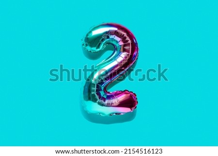 Rainbow foil balloon number, digit two . Top view. Colored numeral on blue background.