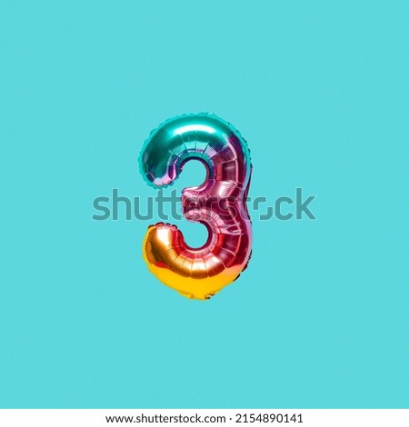 Rainbow foil balloon number, digit three. Top view. Colored numeral on blue background.