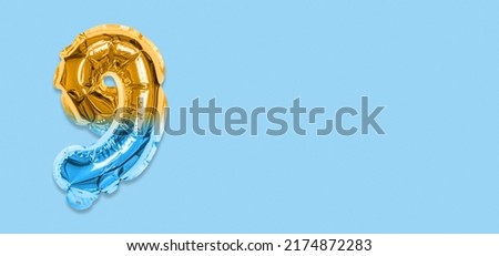 Rainbow foil balloon number, digit nine on a blue background. Birthday greeting card with inscription 9. Top view. Numerical digit. Celebration event, template. Banner.
