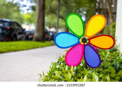 Rainbow garden pinwheel by suburban sidewalk outside home