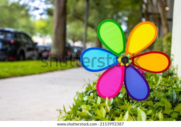 Rainbow\
garden pinwheel by suburban sidewalk outside\
home