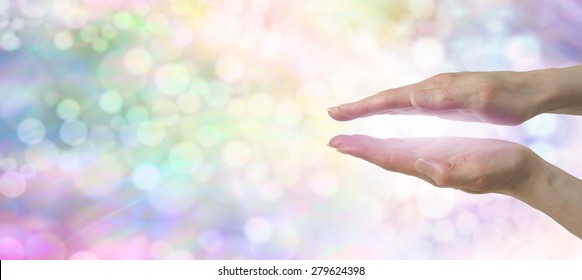 Rainbow Healers Website Banner - Female hands in parallel position with subtle magenta light between on a beautiful rainbow colored bokeh background 