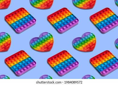 Rainbow heart and square shape isometric pattern of silicon toy for kids. Pop it fidget toy on pastel background. Simle dimple toy on blue pastel background. 