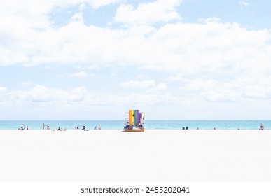 Rainbow Lifeguard Tower on Miami Beach Florida with a Pastel Backdrop of Sand, Sea and Sky, and a Few People Scattered Along the Shore - Powered by Shutterstock