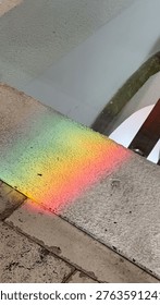 Rainbow light reflection on textured stone ledge inside historic building with soft gradient colors. Light, color and surface concept.