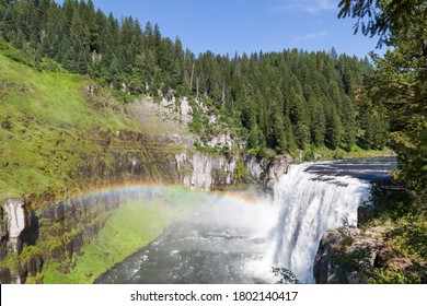 A rainbow in the mist of Upper Mesa Falls as it cascades over a cliff in the rugged wilderness of Henrys Fork of the Snake River along the Mesa Falls Scenic Byway in Idaho.