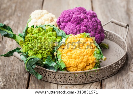 Rainbow of organic cauliflower and Romanesco broccoli on wooden table. Also available in vertical format.