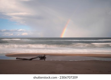 Rainbow over the choppy sea and the beach